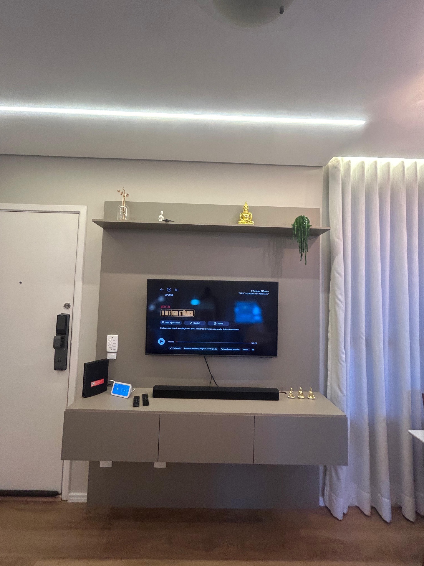 Painel de TV planejado com sanca de LED e fechadura biométrica ao lado
