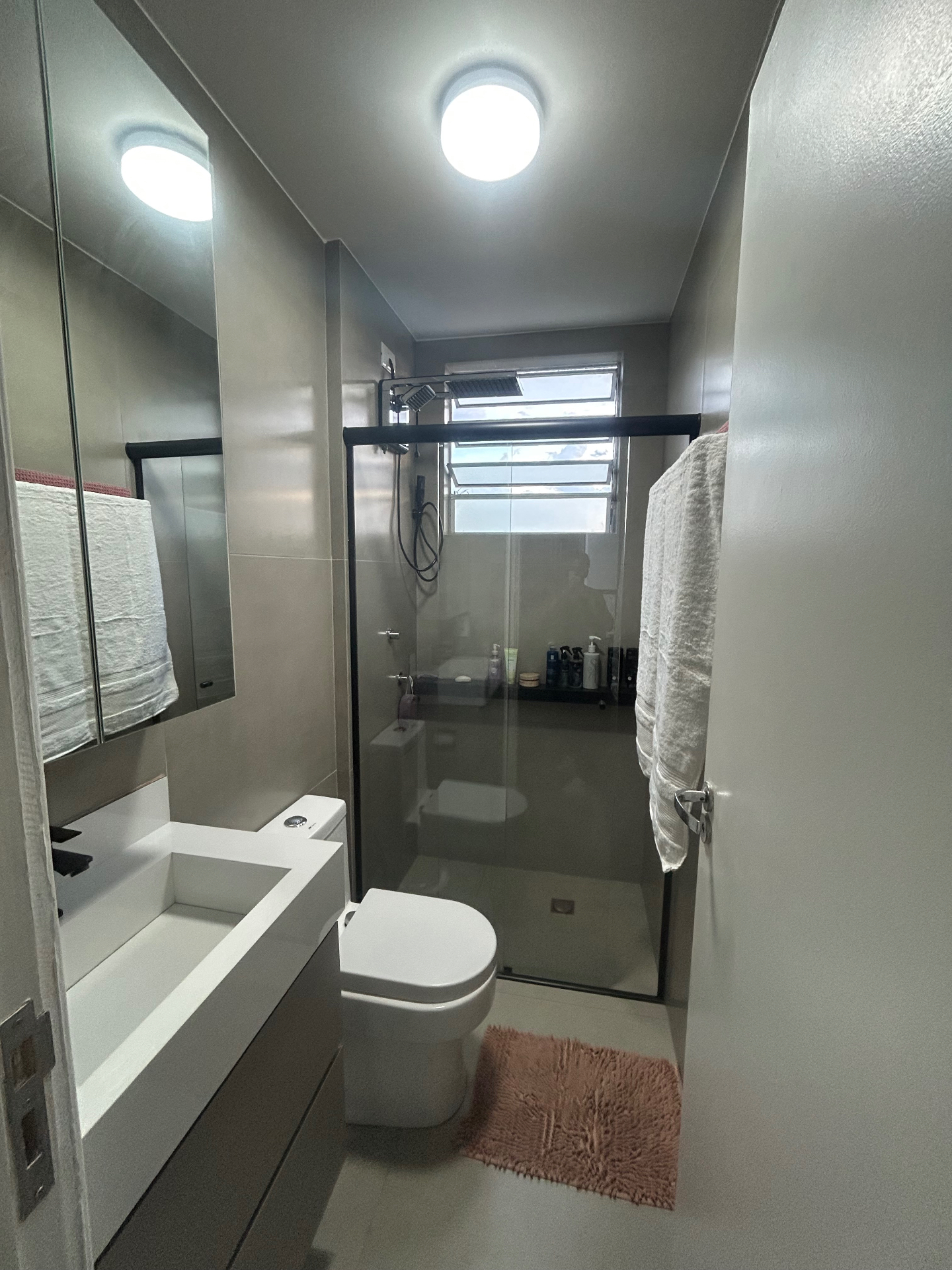 Banheiro completo com box de vidro, chuveiro e bancada planejada